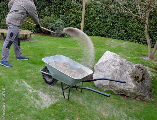 Фотография after pruning a bunch of lawn, gardeners apply silica white sand