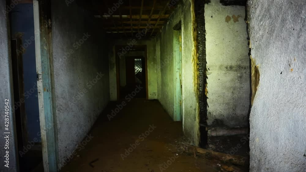man walks through dark abandoned house with flashlight