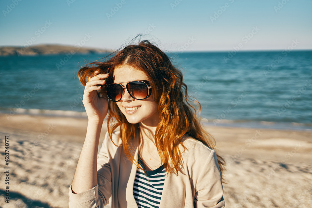 pretty red-haired woman in sunglasses on the beach sand summer model pretty red-haired woman in sunglasses on the beach sand summer model