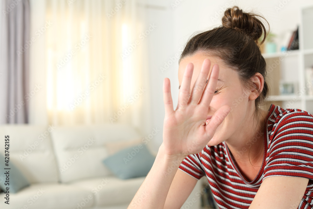 Embarrassed woman avoiding photo shoot at home Embarrassed woman avoiding photo shoot at home