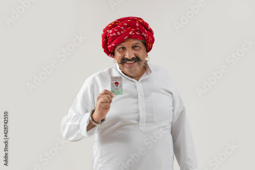 AN ADULT MAN WITH TURBAN HAPPILY SHOWING VOTER ID CARD	 photo
