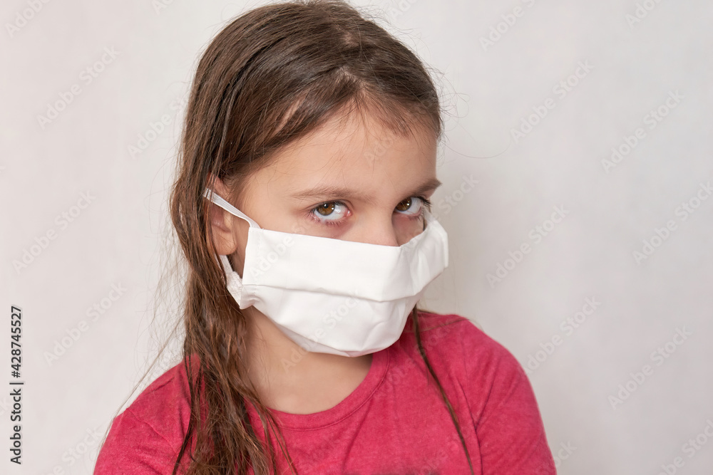 Head portrait of a teenage girl with long hair with a medical mask on her face Head portrait of a teenage girl with long hair with a medical mask on her face