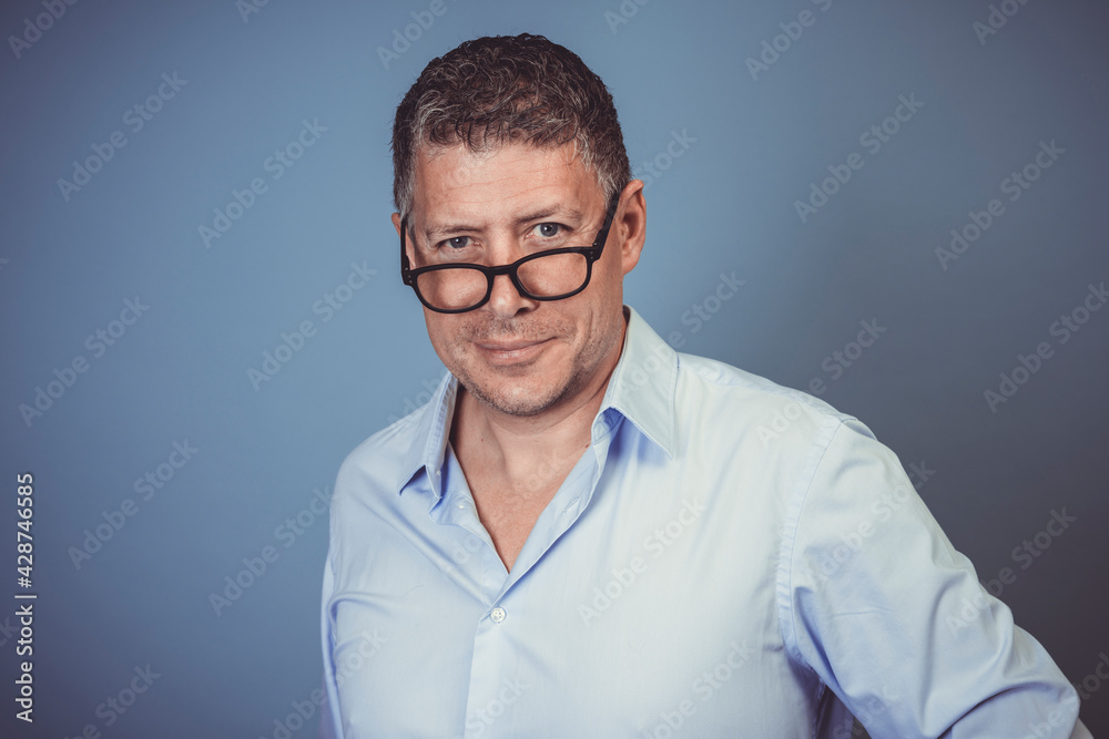 businessman with black glasses and blue shirt posing against blue background in the studio businessman with black glasses and blue shirt posing against blue background in the studio