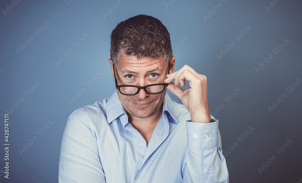 businessman with black glasses and blue shirt posing against blue background in the studio