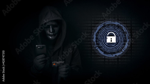 Fototapeta Naklejka Na Ścianę i Meble -  Dangerous anonymous hacker man in hooded and mask use smartphone and credit card, break security data and hack password with key unlocked. Internet crime, cyber attack security concept