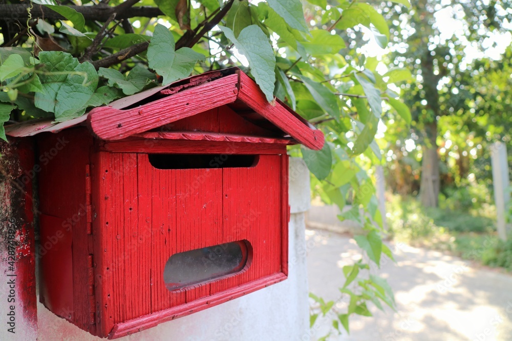 Red wooden mail box in front of a house. Oject and communication concept.