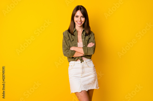 Photo of adorable young lady folded arms beaming smile look camera isolated on yellow color background