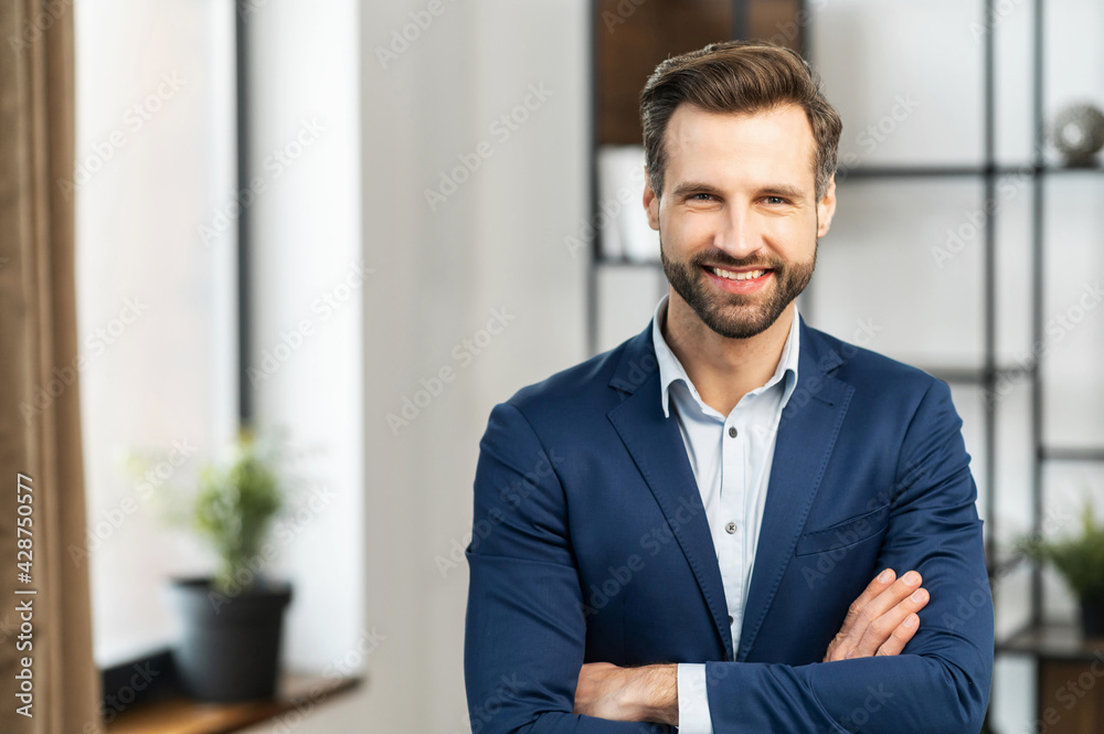 Portrait of successful smiling businessman with bristle, standing with arms crossed over his chest, dressed in white shirt dark blue jacket, freelancer, feels satisfied after successful transaction Portrait of successful smiling businessman with bristle, standing with arms crossed over his chest, dressed in white shirt dark blue jacket, freelancer, feels satisfied after successful transaction