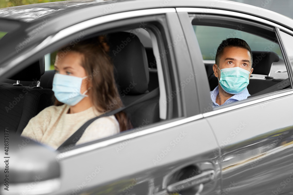 transportation, health and people concept - female driver driving car with male passenger wearing face protective medical mask for protection from virus disease transportation, health and people concept - female driver driving car with male passenger wearing face protective medical mask for protection from virus disease