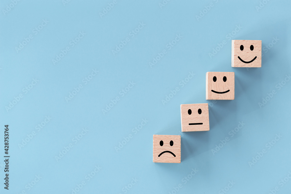 Close up top view customer hand choose smiley face on wood cube, Service rating, satisfaction concept. Close up top view customer hand choose smiley face on wood cube, Service rating, satisfaction concept.