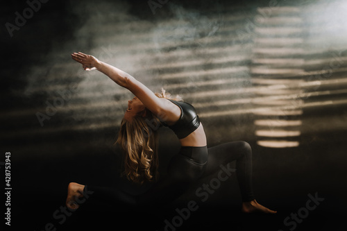 Frau macht Yoga entspannt, kraftvoll, Balance, Üben, Fitness, dunkler Hintergrund, Lichteinfall, Nebel, Lunge Pose, Ashva Sanchalanasana photo