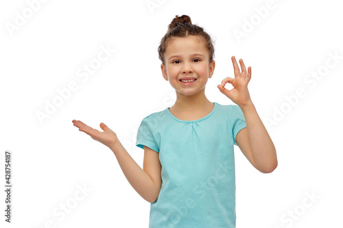 childhood, fashion and people concept - happy smiling girl holding something imaginary over white background