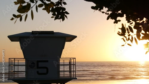 Lifeguard watch tower, sunny sunset beach, Oceanside USA. Rescue station, waterfront watchtower hut and tree leaves, pacific ocean coast atmosphere. California summertime aesthetic, Los Angeles vibes.