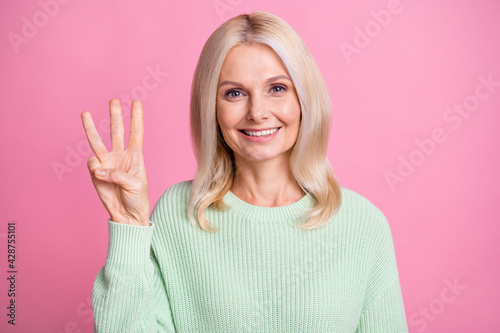 Fotografija Photo portrait of elderly woman showing three fingers isolated on pastel pink co