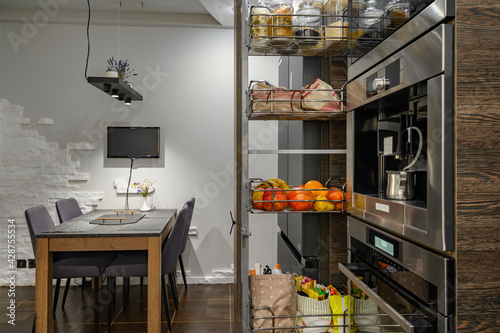 Modern luxury large brown kitchen with dining table and vertical drawer pulled out photo