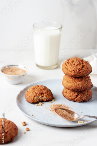 Freshly Homemade baked ginger cookies with cinnamon and sugar on gray plate and glass of milk  light marble background.