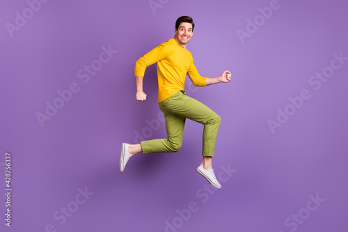 Full size profile side photo of young handsome happy positive man running in air isolated on purple color background