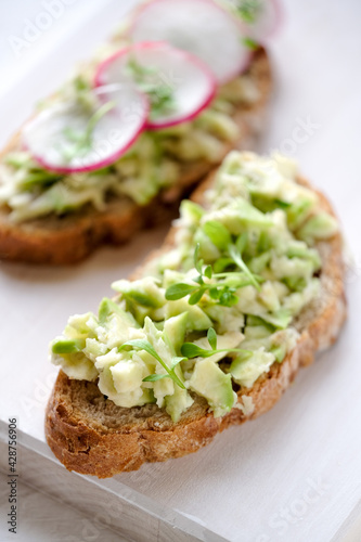 Fresh green spring sandwich with avocado and radish at light background. Copyspace