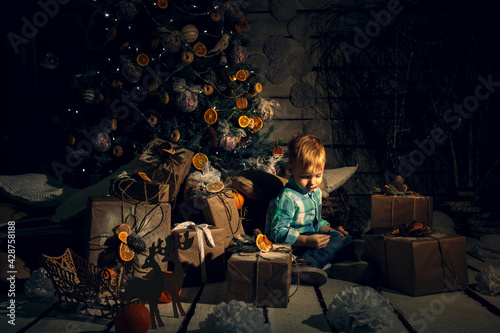 New year activity indoor. Happy Baby Near Christmas Tree With Gifts and mandarines. Fabulous fairytale plot