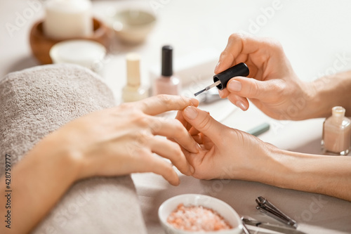 Woman applying nail polish at nail salon photo