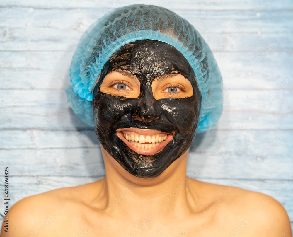 Woman relaxing with black charcoal facial mask Woman relaxing with black charcoal facial mask