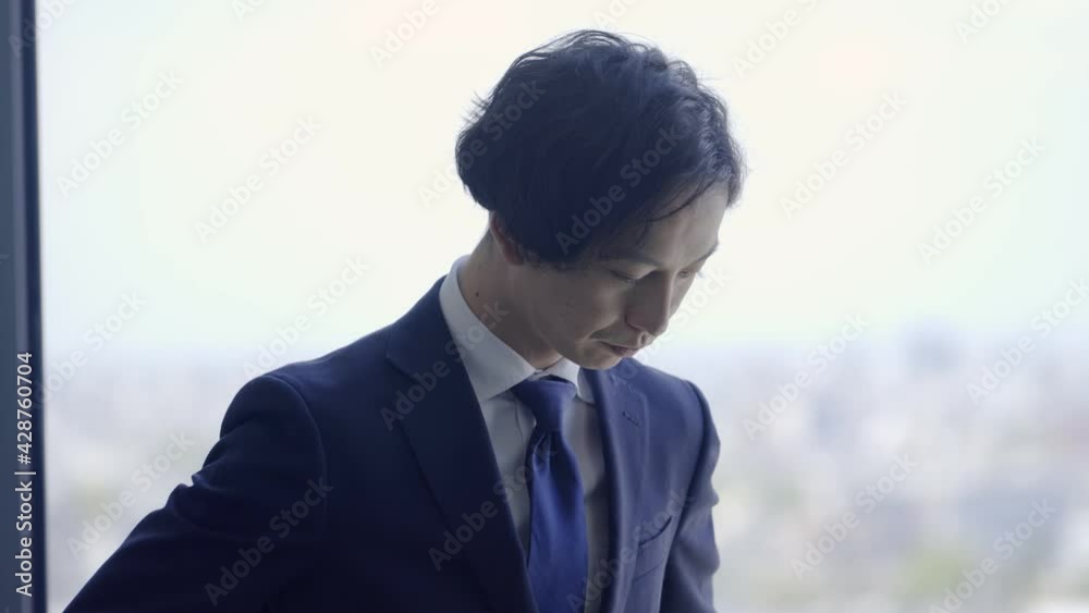 窓の外を見て考え事をするビジネスマン