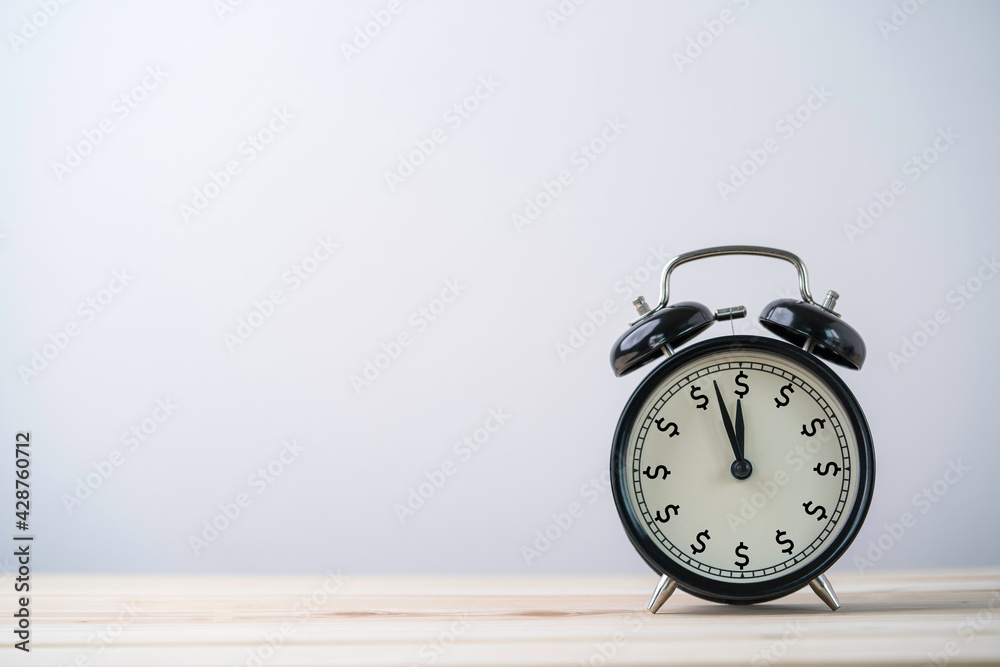USD dollar sign print screen on alarm clock on wooden table with copy space , Money and time management concept. USD dollar sign print screen on alarm clock on wooden table with copy space , Money and time management concept.