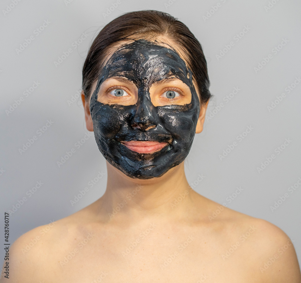 Woman relaxing with black charcoal facial mask Woman relaxing with black charcoal facial mask