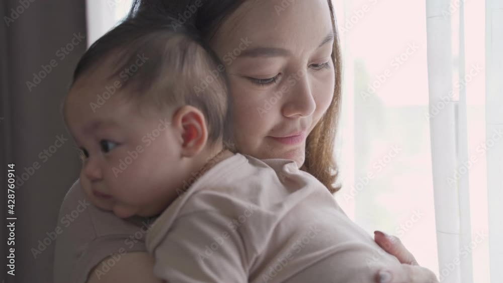 asian woman mother parent embracing baby infant lull and calm baby down near window at home. mom holding newborn baby with love and protection. kid trust parent. asian woman mother parent embracing baby infant lull and calm baby down near window at home. mom holding newborn baby with love and protection. kid trust parent.