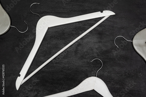 Photos White wooden hangers on black background, top view