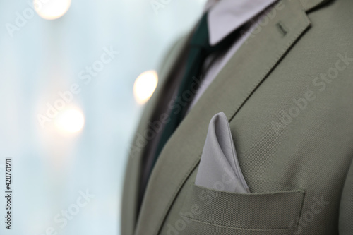 Man with handkerchief in suit pocket against blurred lights, closeup. Space for text © New Africa