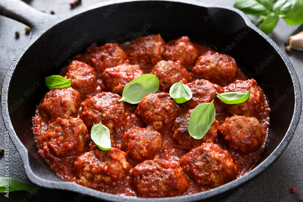 Meat balls with tomato sauce with garlic and basil in a frying pan on a brown background. Meat balls with tomato sauce with garlic and basil in a frying pan on a brown background.