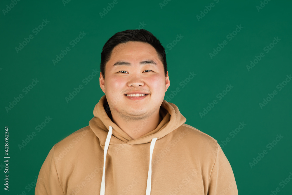 Asian man's portrait isolated over green studio background with copyspace
