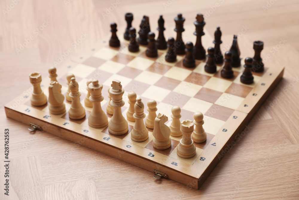 Chess board with pieces on wooden table