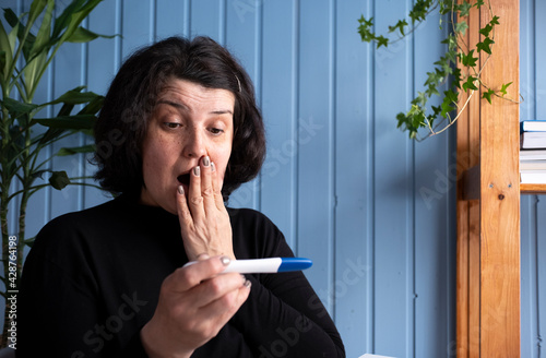 Middle aged old woman looking at pregnancy test result showing positive excited for motherhood. PInfertility or IVF concept