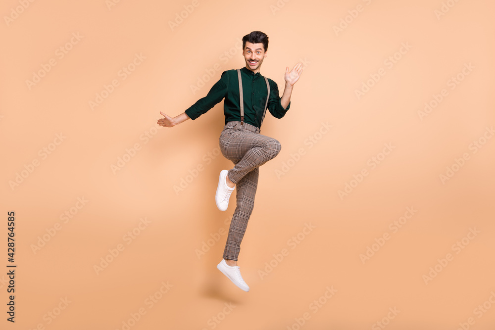 Full body photo of funky attractive young man jump up air good mood isolated on pastel beige color background