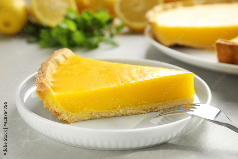 Slice of delicious homemade lemon pie on light grey table Slice of delicious homemade lemon pie on light grey table