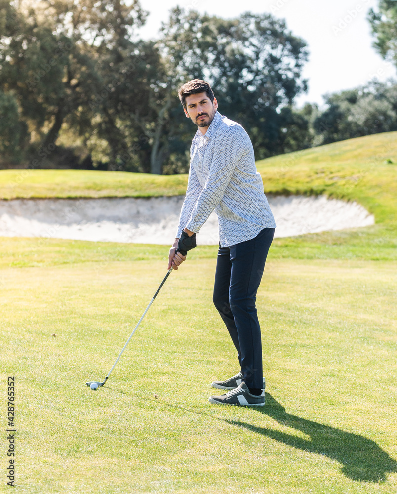 Fototapeta premium A young Caucasian male playing golf on a professional golf course