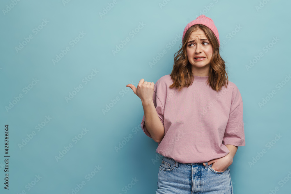 Young upset woman frowning and pointing finger aside Young upset woman frowning and pointing finger aside