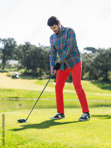 A young Caucasian male playing golf on a professional golf course