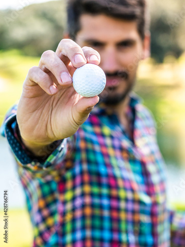 A Caucasian male holding and showing a golf ball