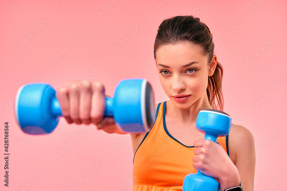 Cute athletic girl in sportswear with dumbbells isolated on pink background. Sports, yoga, active lifestyle, exercise for health. Cute athletic girl in sportswear with dumbbells isolated on pink background. Sports, yoga, active lifestyle, exercise for health.