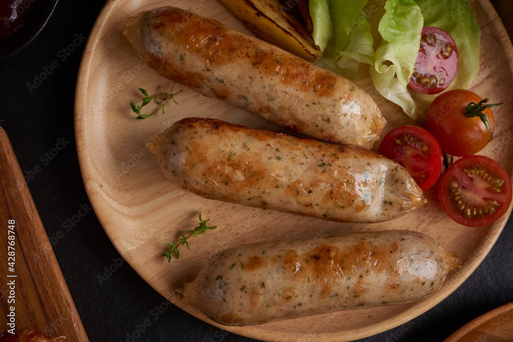 sausages and ingredients for cooking. Grilled sausage with the addition of herbs and and spices, vegetables, rosemary, thyme on the grill plate, Grilling food, bbq, barbecue, on stone table. Top view.