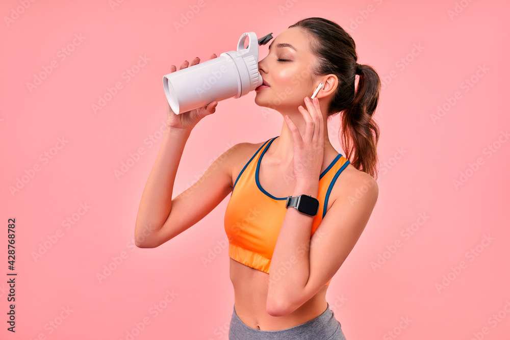 Cute athletic girl in sportswear with protein shake isolated on