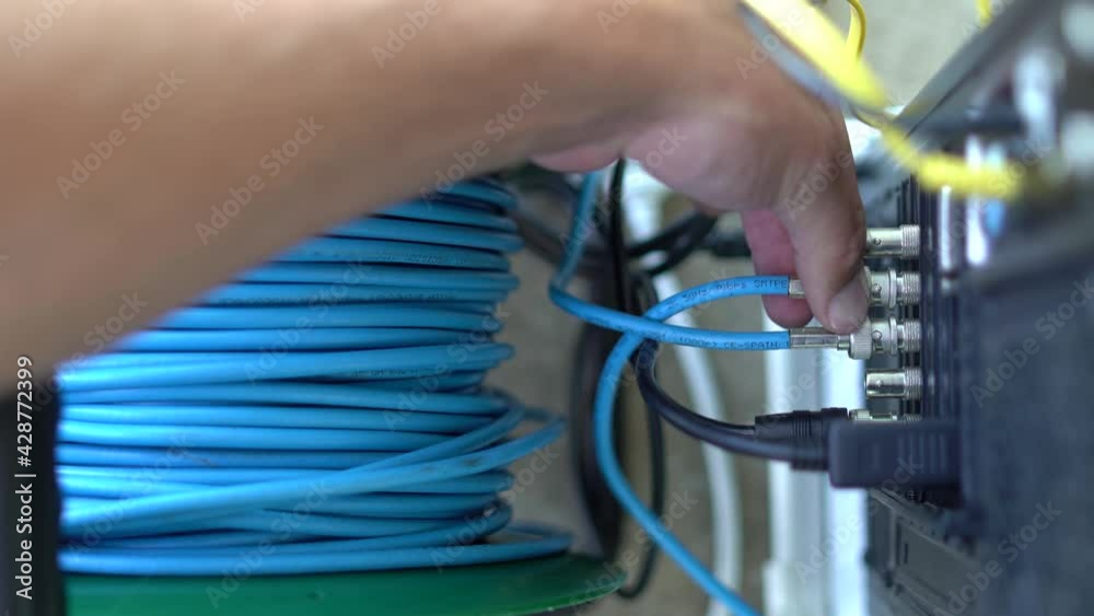 Mano de una persona conectando un cable sdi azul en un pc