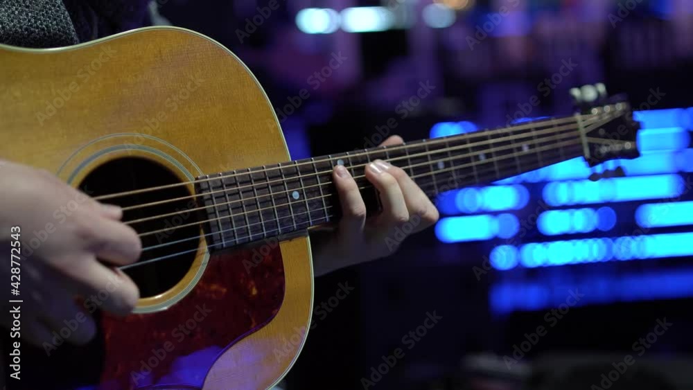 Mano de musico tocando una guitarra acustica con el fondo desenfocado