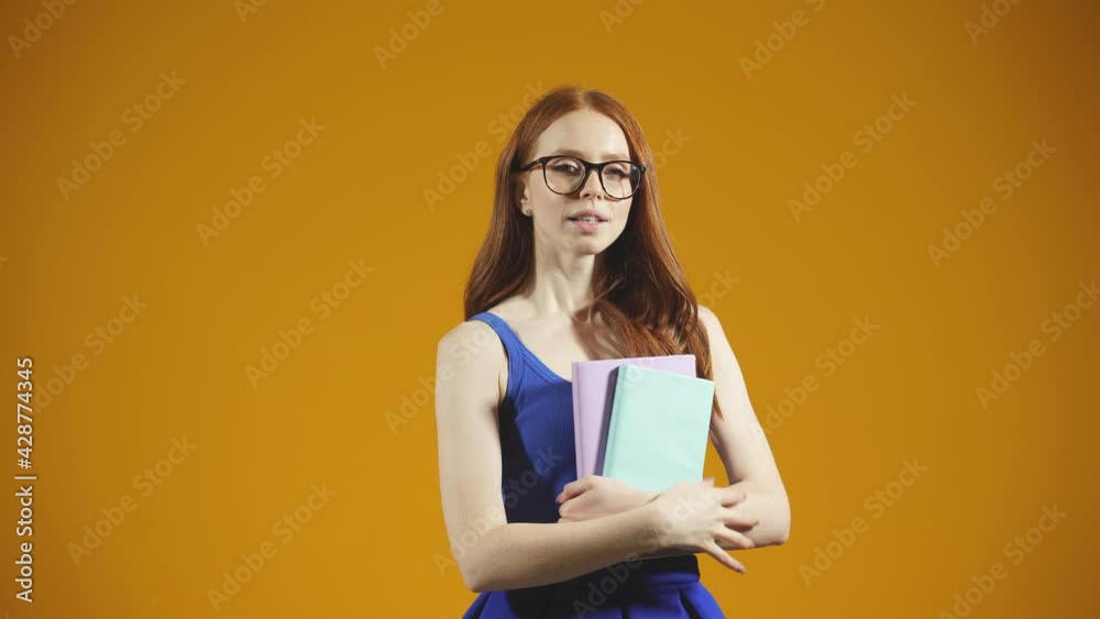 Portrait of a young student on an isolated background, a young woman with glasses holding books, notebooks Portrait of a young student on an isolated background, a young woman with glasses holding books, notebooks