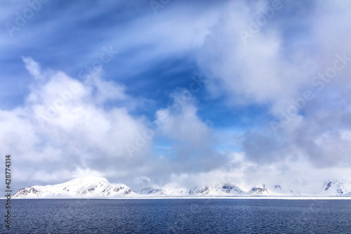 Pristine snow covered mountains and blue summer sky  Svalbard