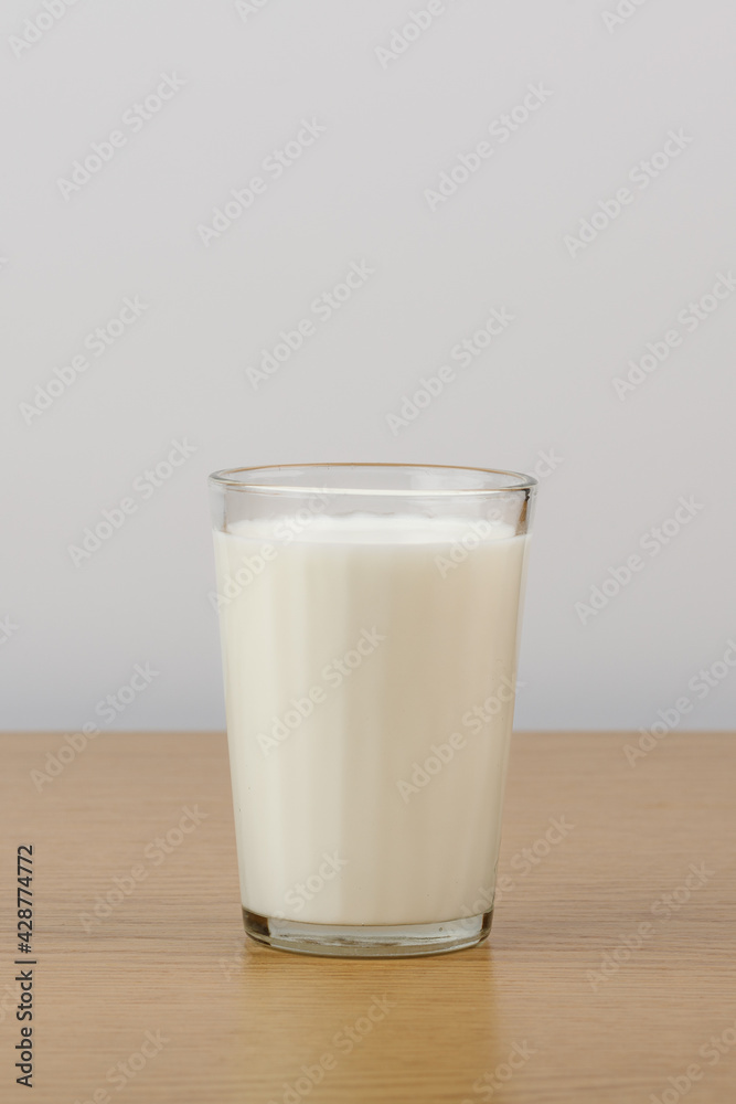 A glass of milk on a wooden table on a white background A glass of milk on a wooden table on a white background