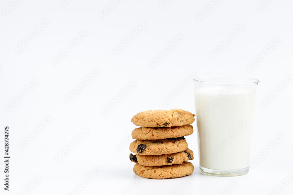 A glass of milk and cookies with raisins on a white background A glass of milk and cookies with raisins on a white background